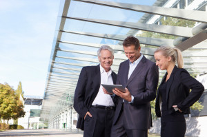 Germany, Bavaria, Munich, Business people using digital tablet, smiling