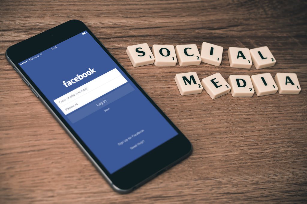Phone with Facebook Login and the words social media in Scrabble Tiles