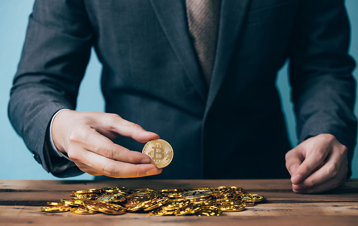 Close-up of businessman counting and holding bitcoin sign of coins - indicating cryptocurrency financial trade wealth and business investment