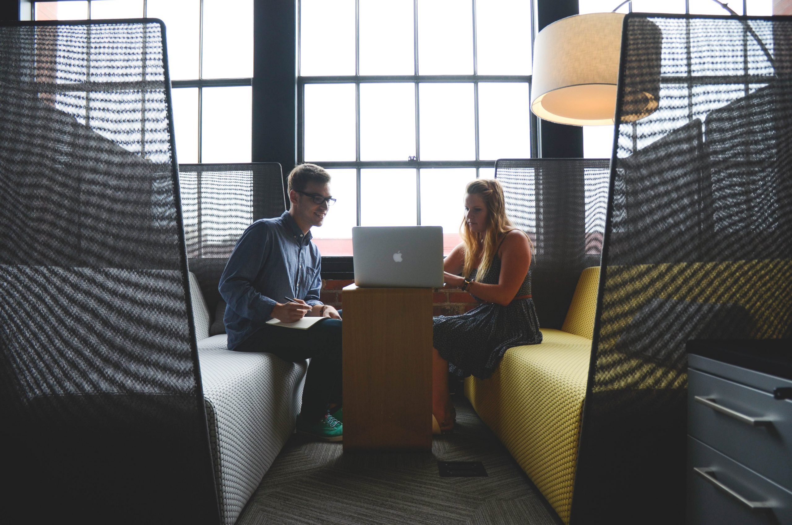 Two coworkers sit in front of a laptop