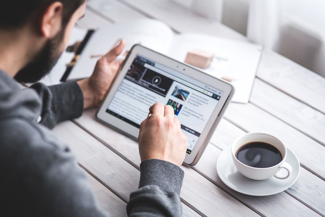 a man scrolling through a blog on a touchscreen tablet