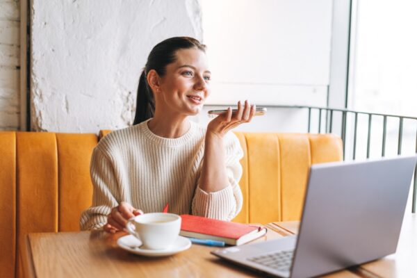 young-woman-smiling-with-cup-using-mobile-phone