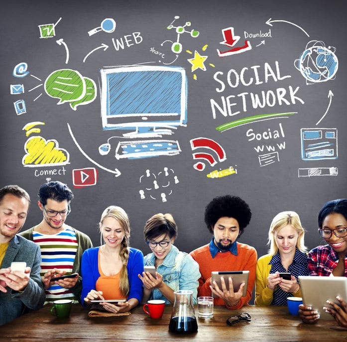 Kids sitting at a table looking at social media on phones and computers. Above them is an illustration of a computer and different social media related images.