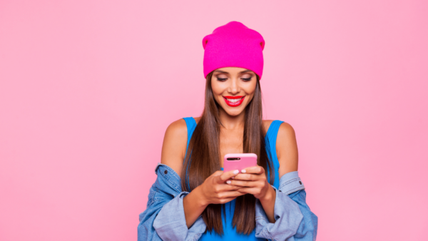 woman in pinik beanie typing on phone