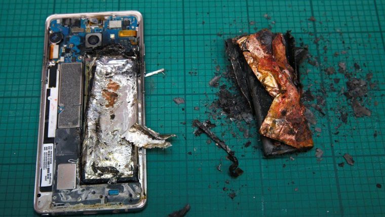 the back of a phone and a burnt phone battery on a green table