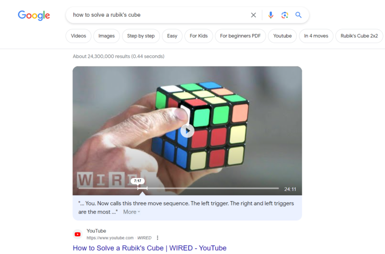 Screenshot of Google's first page for the keyword "how to solve a rubik's cube." The featured snippet is video content