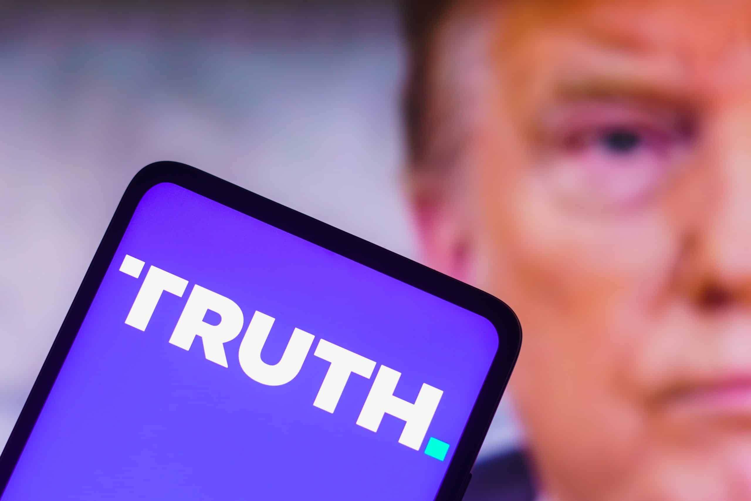 Truth Social logo on a phone in front of Donald Trump