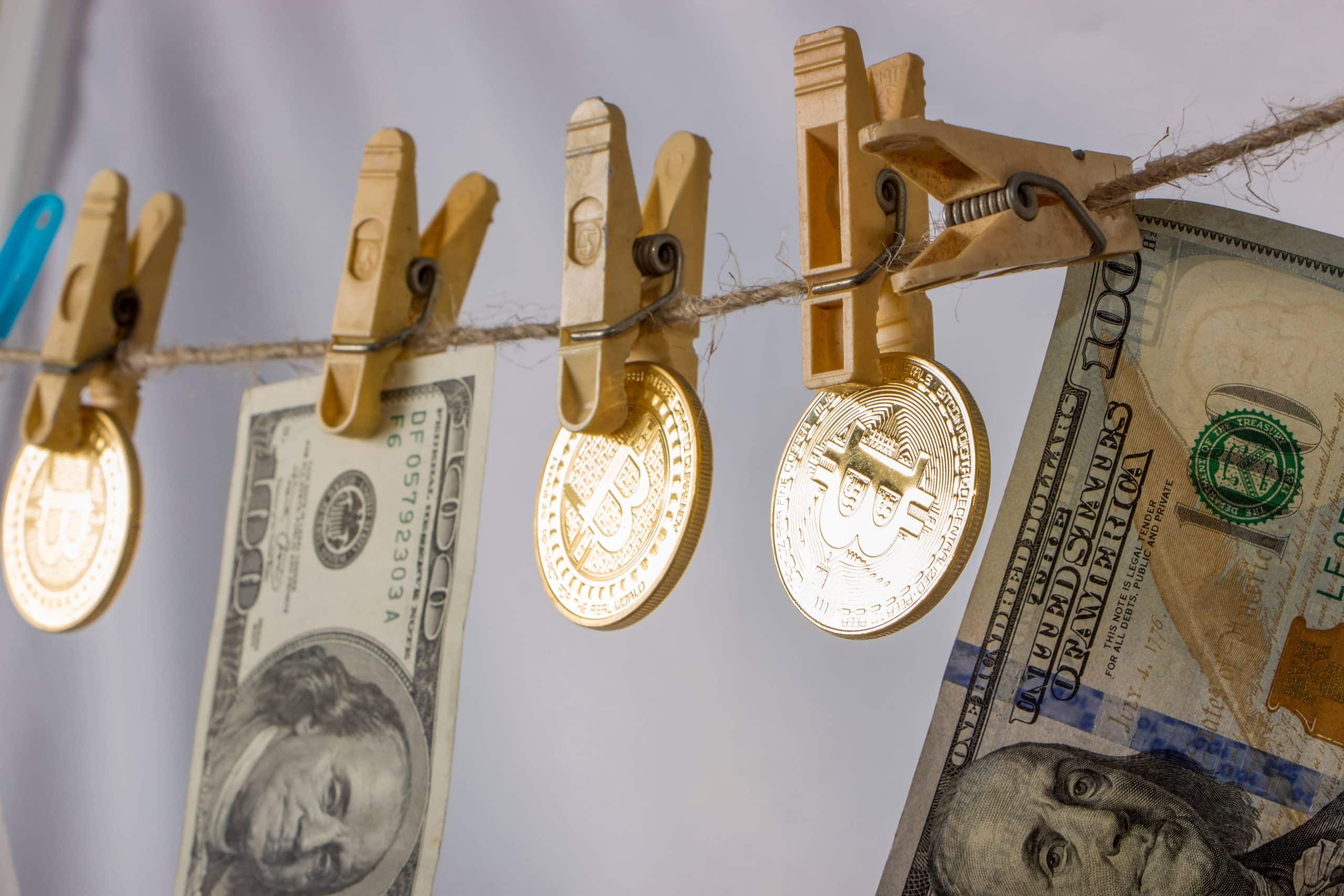 bitcoin coins and hundred dollar bills on clothesline