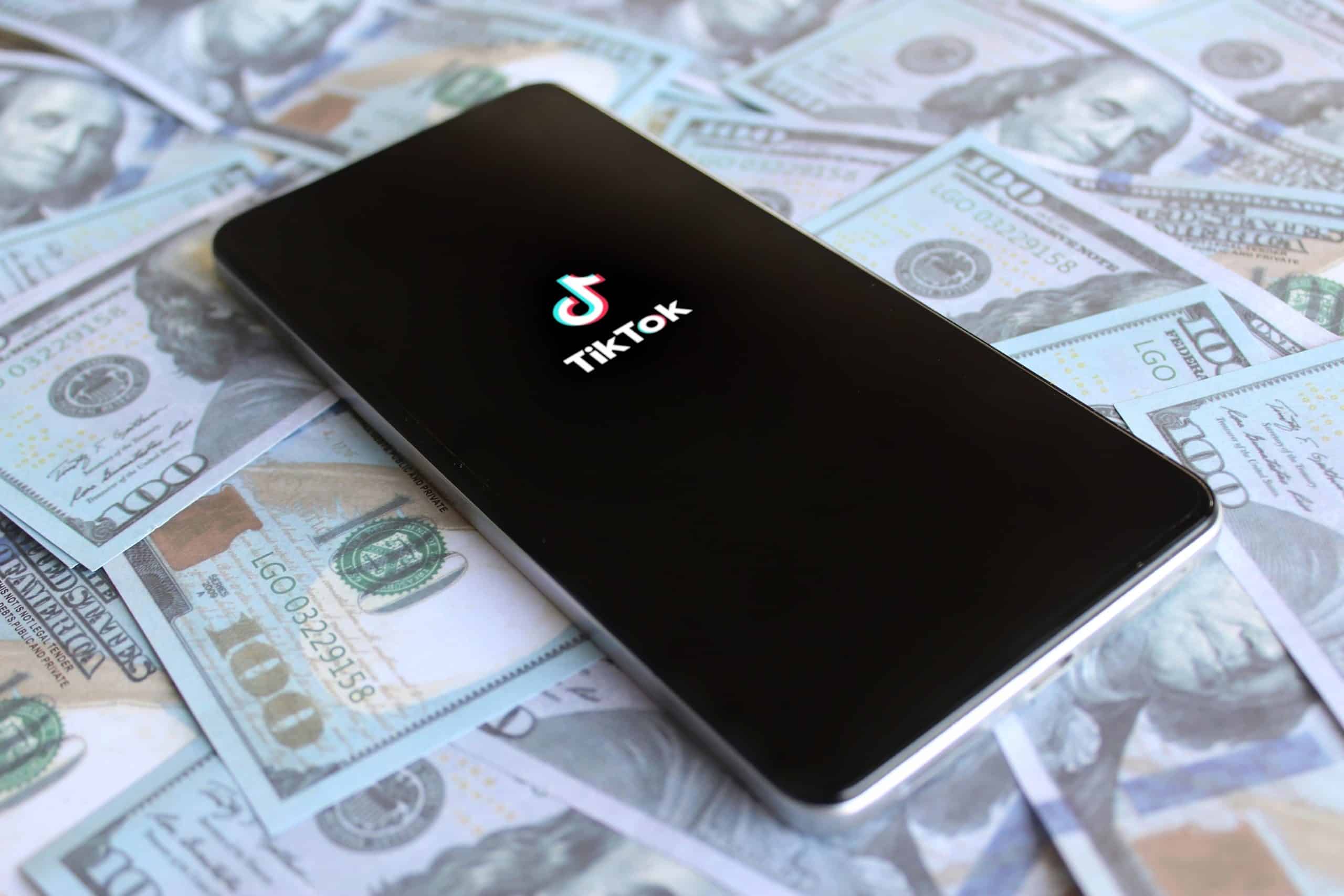 TikTok logo on a phone on 100 dollar bills